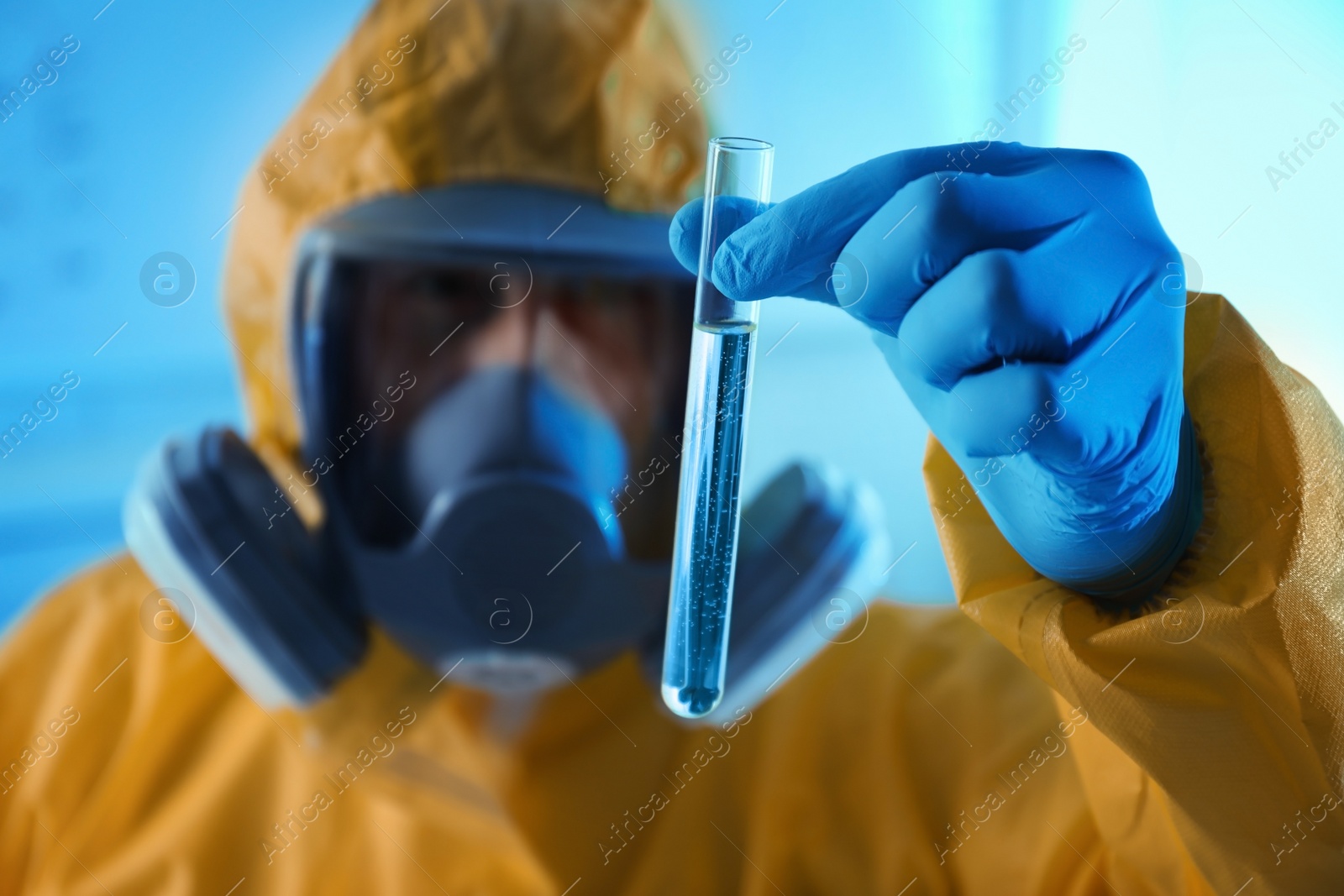 Photo of Scientist in chemical protective suit with test tube at laboratory, focus on hand. Virus research