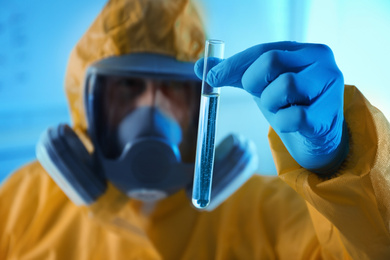 Photo of Scientist in chemical protective suit with test tube at laboratory, focus on hand. Virus research