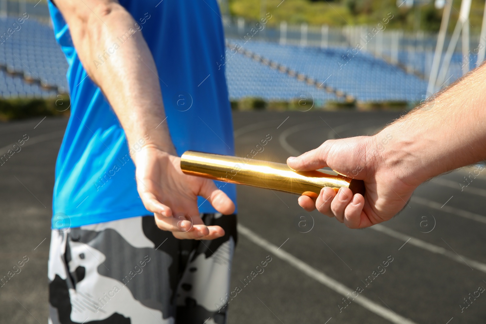 Photo of Man passing baton to his partner at stadium, closeup