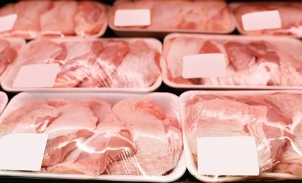 Photo of Shelf with packed chicken meat in supermarket