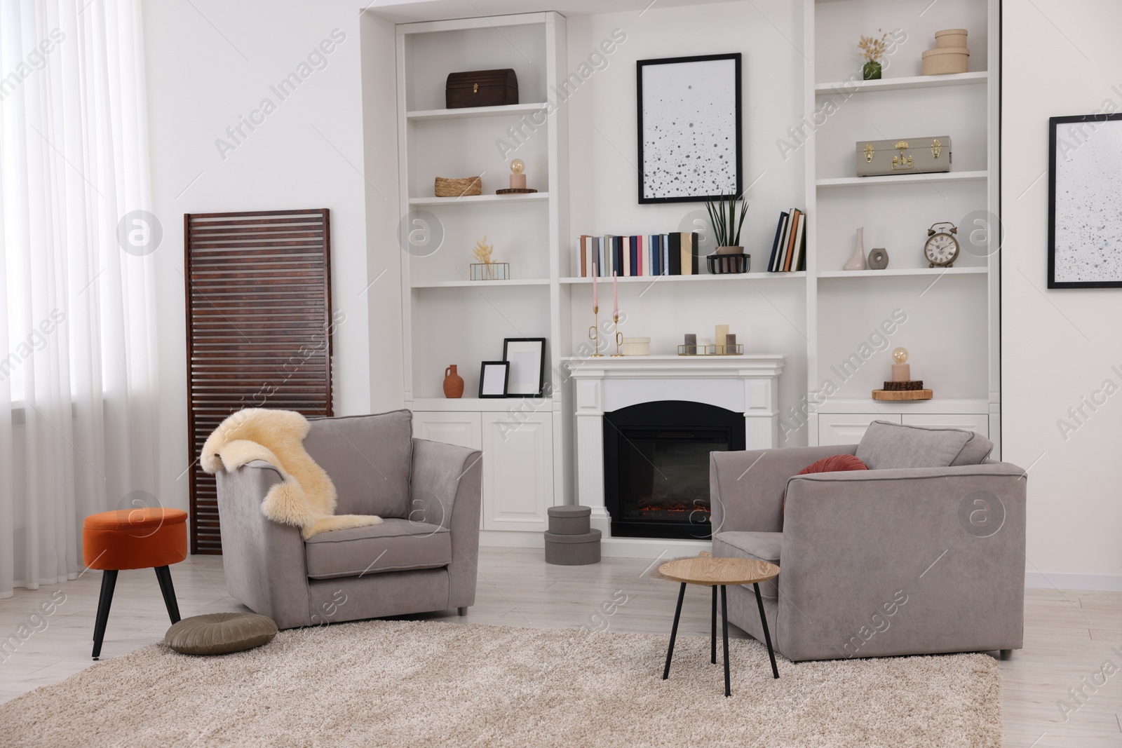 Photo of Comfortable armchairs, fireplace and shelves in living room. Interior design