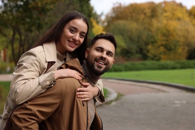 Romantic young couple spending time together in autumn park, space for text