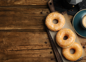 Delicious donuts on wooden table, flat lay. Space for text