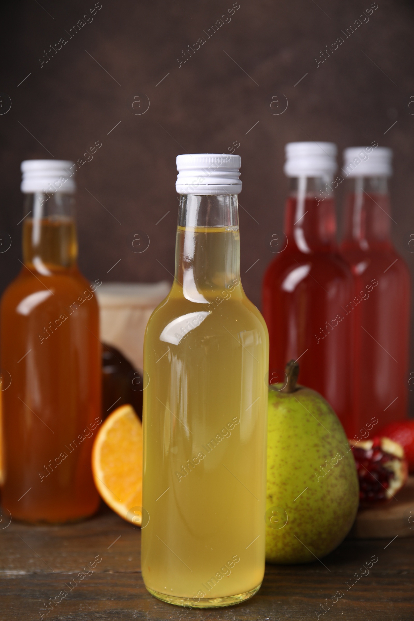 Photo of Delicious kombucha in glass bottles and fresh fruits on wooden table