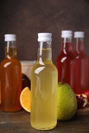 Delicious kombucha in glass bottles and fresh fruits on wooden table