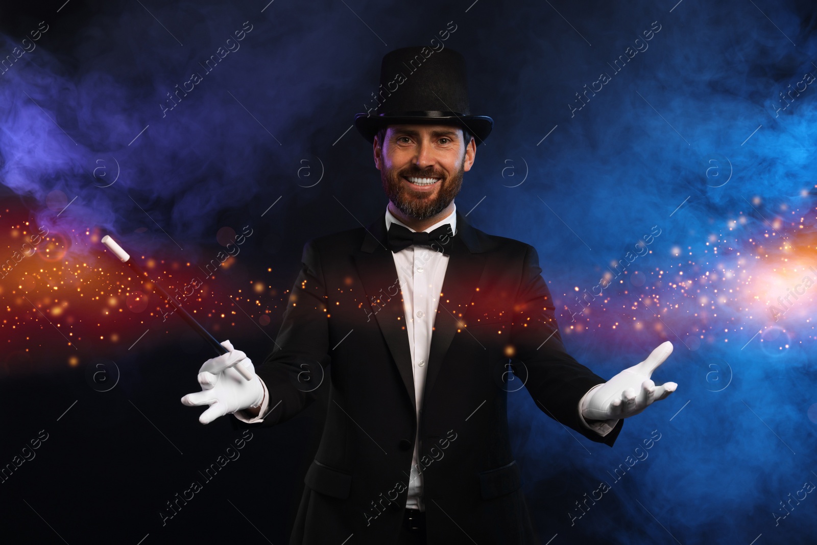 Image of Smiling magician with wand showing trick on dark background