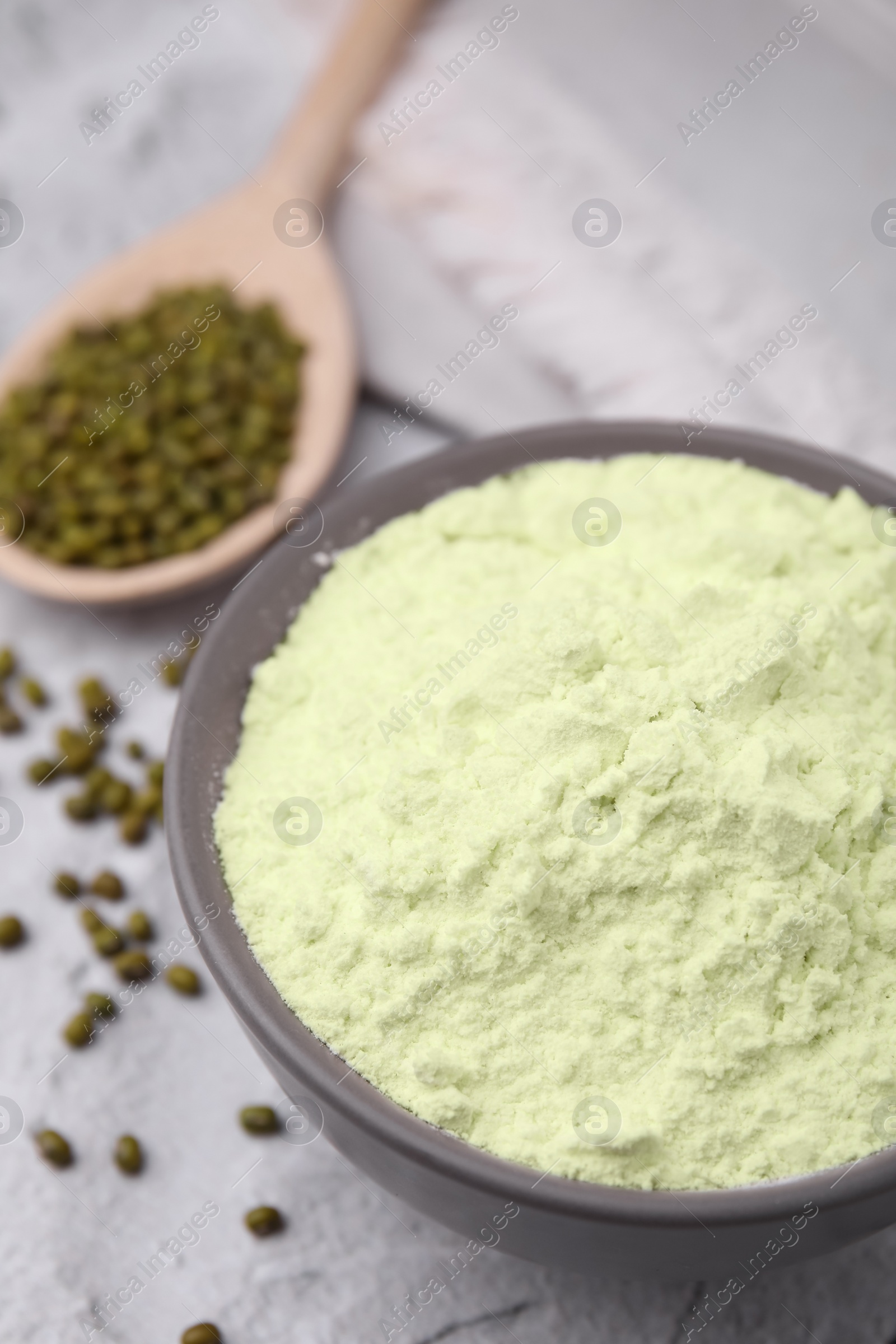 Photo of Mung bean flour in bowl and seeds on white textured table