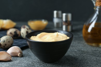 Photo of Delicious homemade mayonnaise with ingredients on grey table