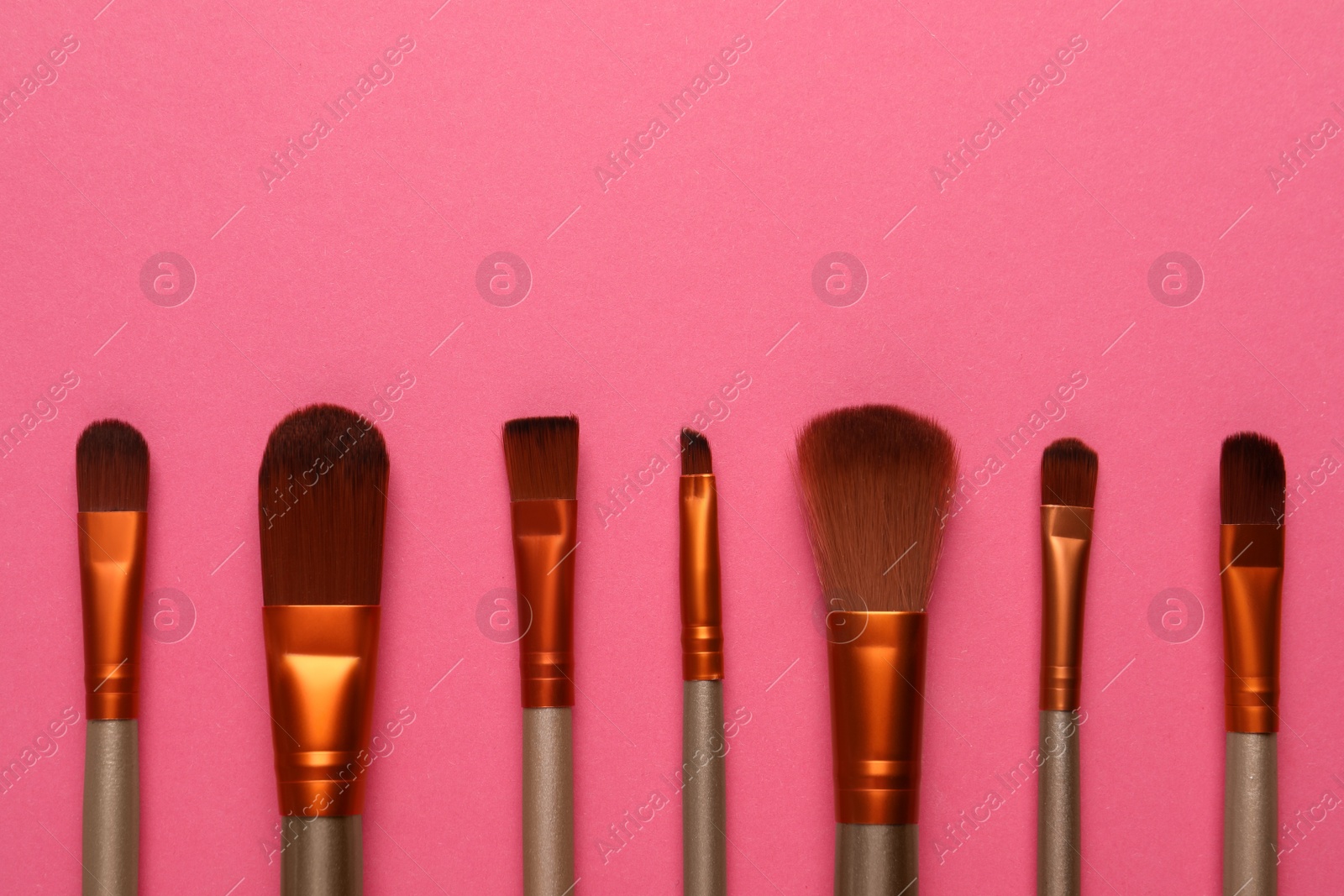 Photo of Set of makeup brushes on pink background, flat lay. Space for text