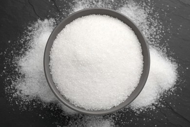 Photo of Granulated sugar on black table, top view