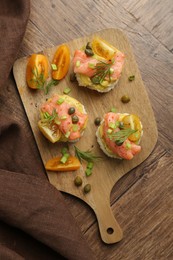 Tasty canapes with salmon served on wooden table, top view