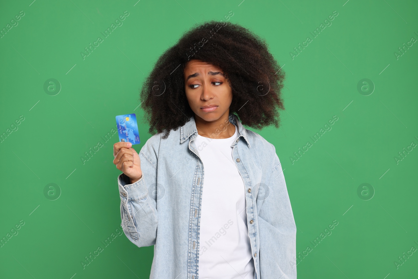 Photo of Confused woman with credit card on green background. Debt problem
