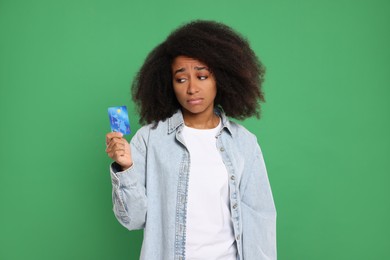 Photo of Confused woman with credit card on green background. Debt problem