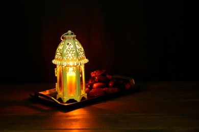 Photo of Decorative Arabic lantern and dates on table against dark background. Space for text