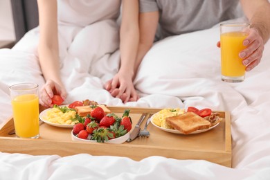 Photo of Couple eating tasty breakfast in bed, closeup