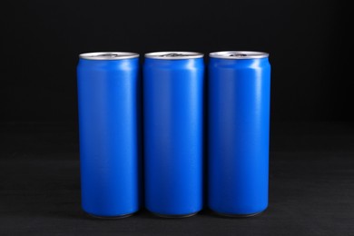 Energy drinks in blue cans on black wooden table