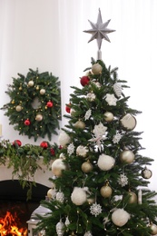 Beautiful Christmas tree with star topper in decorated room