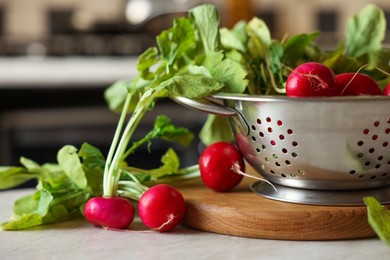 Photo of Metal colander with fresh radishes on white table, closeup