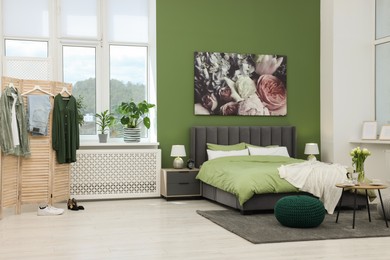 Stylish bedroom with comfortable bed, bedside tables and vase of tulips. Interior design