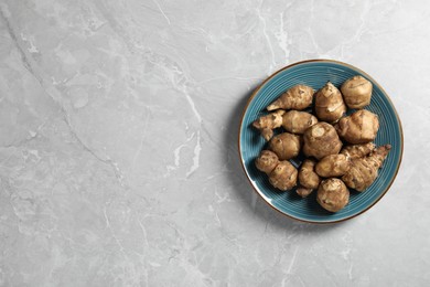 Photo of Jerusalem artichokes on light grey marble table, top view. Space for text