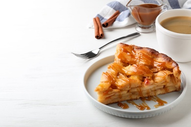 Photo of Slice of traditional apple pie served with coffee on white wooden table. Space for text