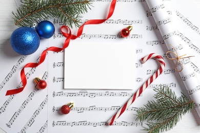 Photo of Flat lay composition with Christmas decorations and blank paper on music sheets