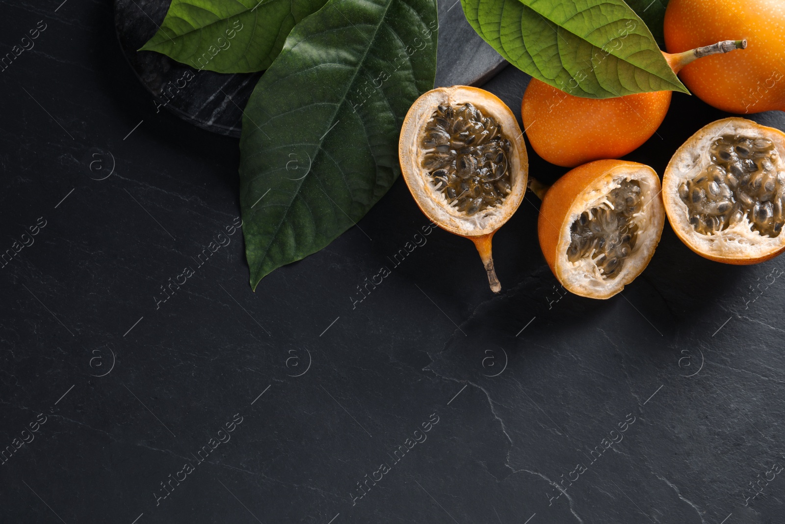 Photo of Delicious ripe granadillas on black table, above view. Space for text