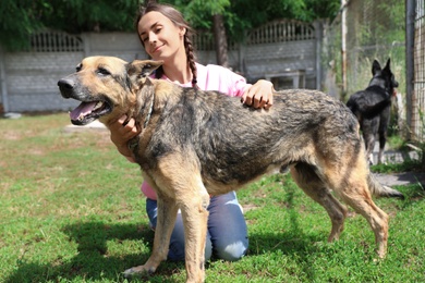 Photo of Female volunteer with homeless dog at animal shelter outdoors