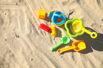 Different child plastic toys on sandy beach, flat lay. Space for text