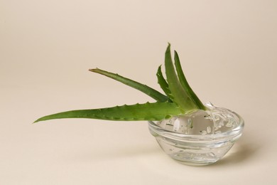 Photo of Bowl with natural gel and fresh aloe on beige background, closeup