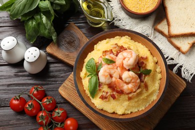 Photo of Fresh tasty shrimps, bacon, grits and basil in bowl on wooden table, flat lay