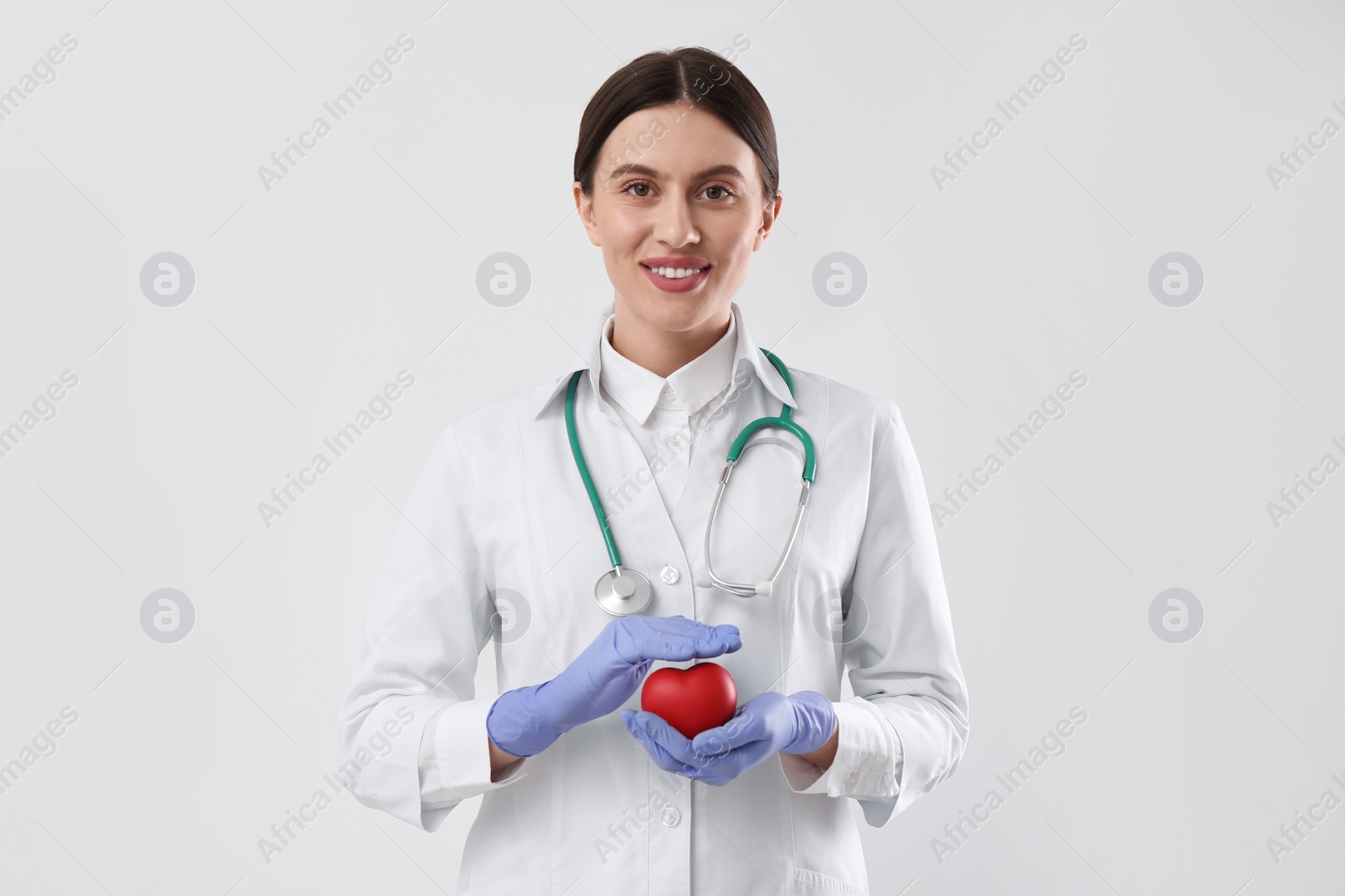 Photo of Doctor with stethoscope and red heart on white background. Cardiology concept