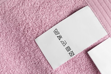 Clothing label on pink fluffy towel, top view. Space for text