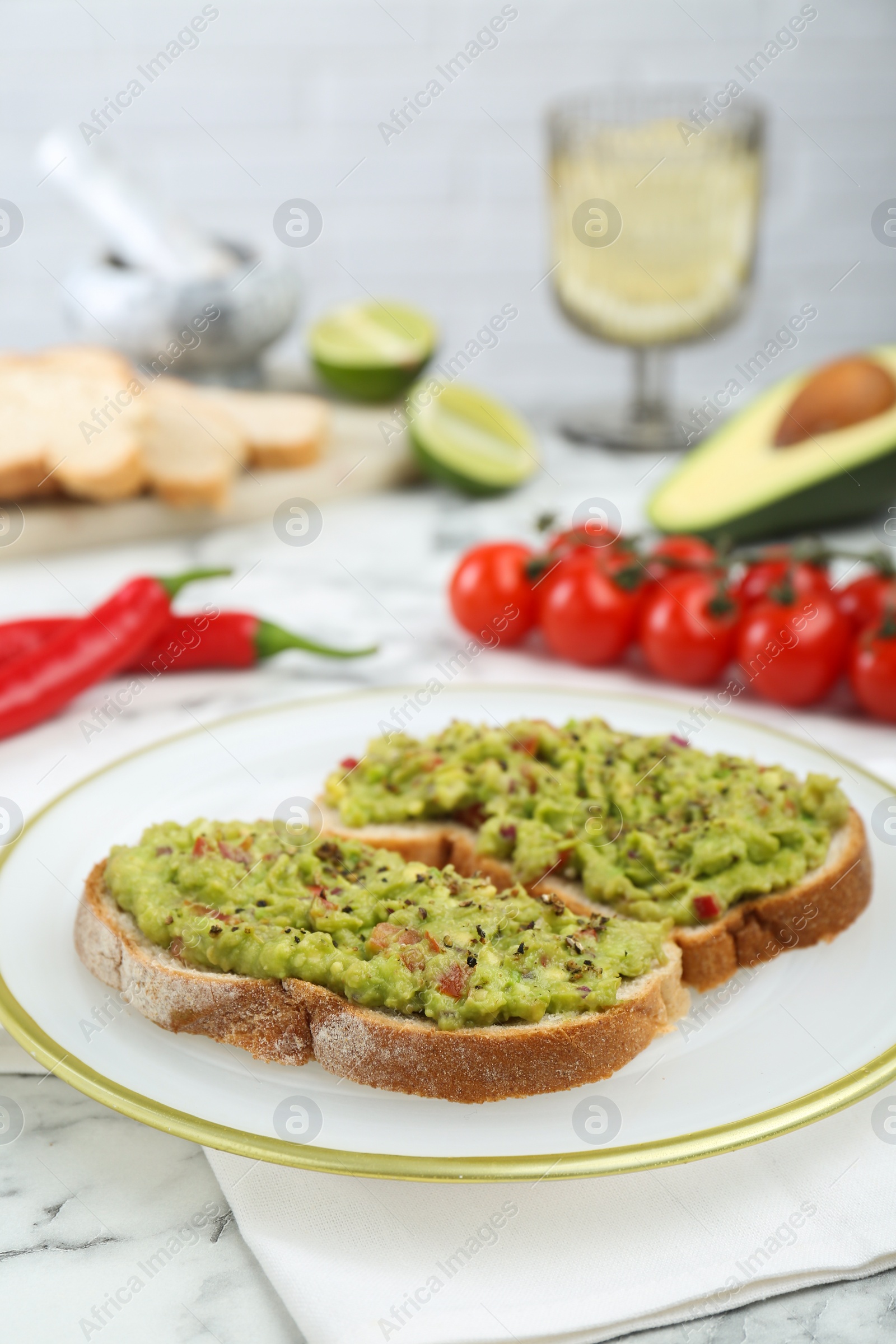 Photo of Delicious sandwiches with guacamole and ingredients on white table