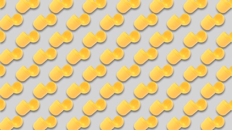 Mykolaiv, Ukraine - June 26, 2023: Open yellow plastic capsule from Kinder Surprise Egg on grey background, seamless pattern design