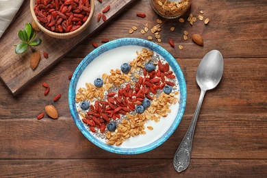 Photo of Flat lay composition of smoothie bowl with goji berries on wooden table