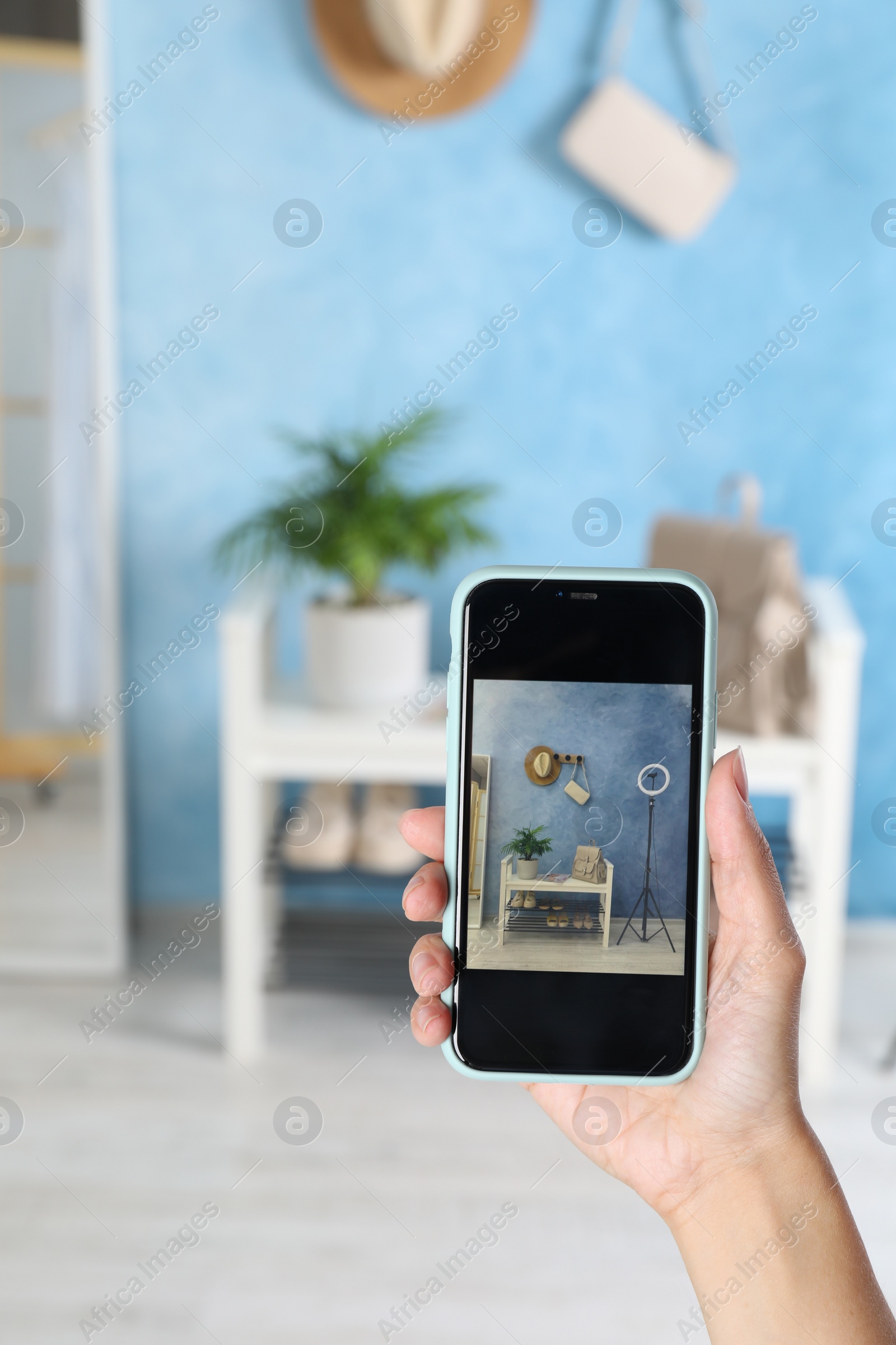 Photo of Blogger taking photo of shelving unit with stylish shoes indoors, closeup