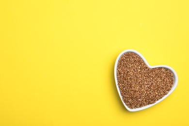 Photo of Buckwheat grains on yellow background, top view. Space for text