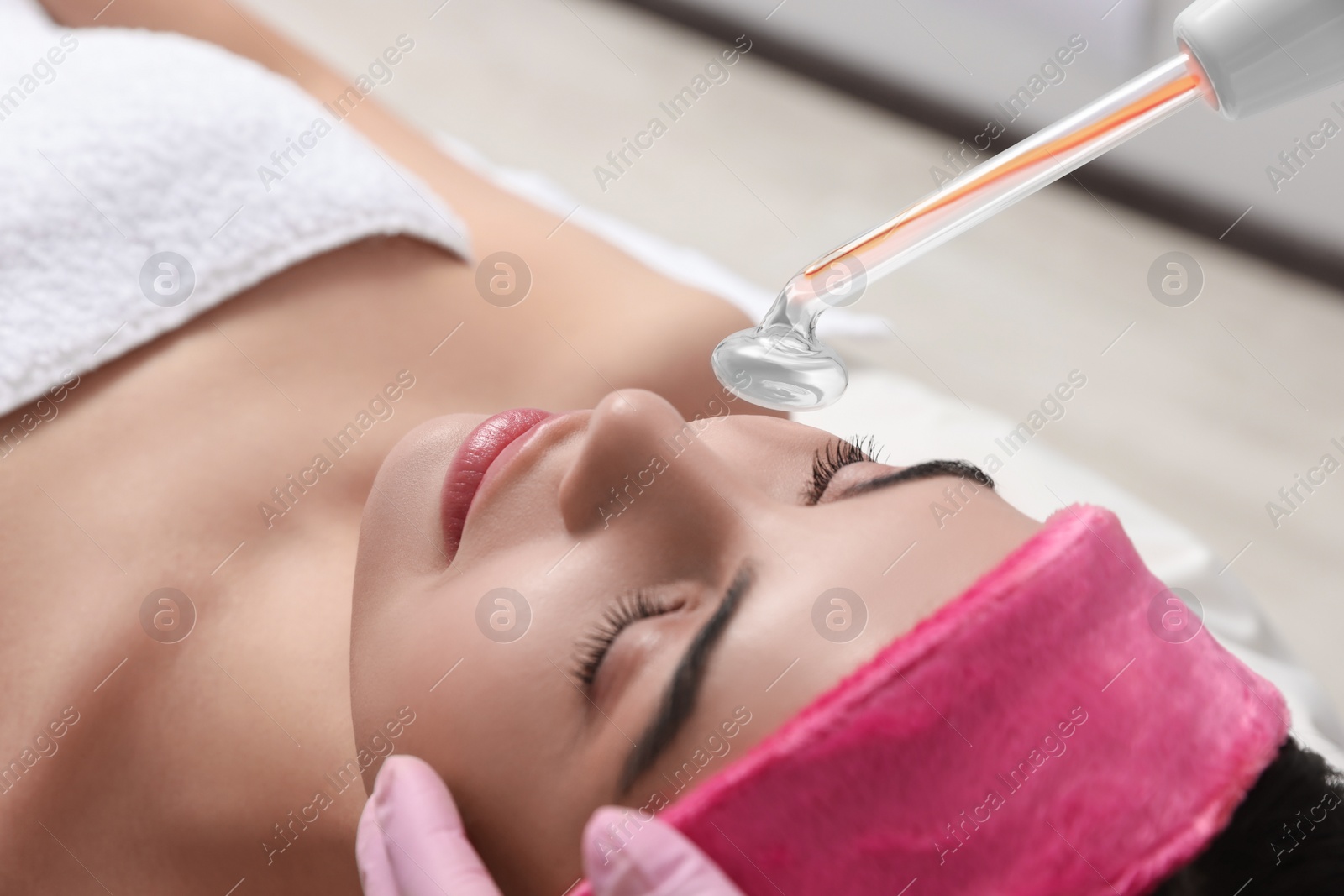 Photo of Young woman undergoing face rejuvenation procedure with darsonval in salon, closeup