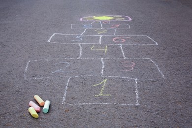 Photo of Hopscotch drawn with colorful chalk on asphalt outdoors, closeup