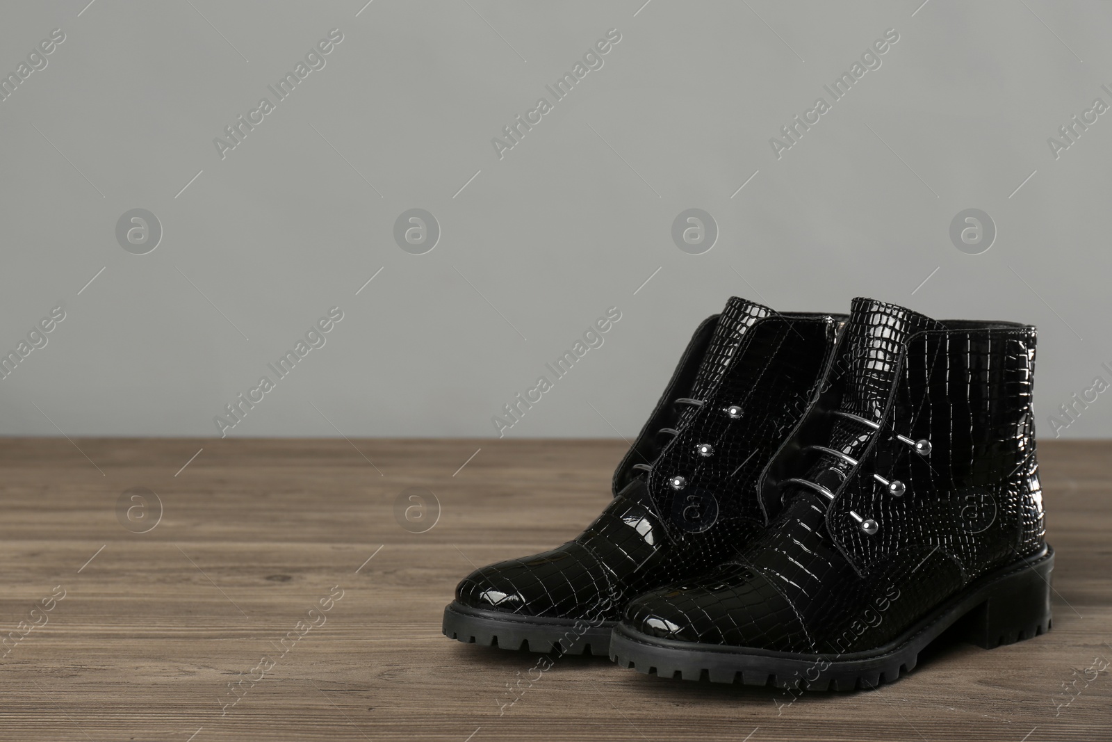 Photo of Pair of stylish ankle boots on wooden background. Space for text