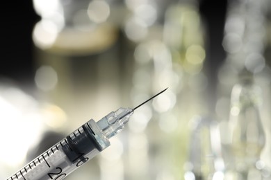 Syringe with medicine against blurred background, closeup. Space for text