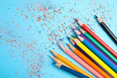 Color pencils and shavings on blue background, flat lay