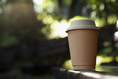 Photo of Cardboard takeaway coffee cup with lid on blurred background, space for text