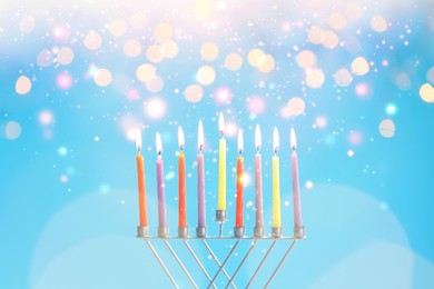 Hanukkah celebration. Menorah with burning candles on light blue background with blurred lights, closeup