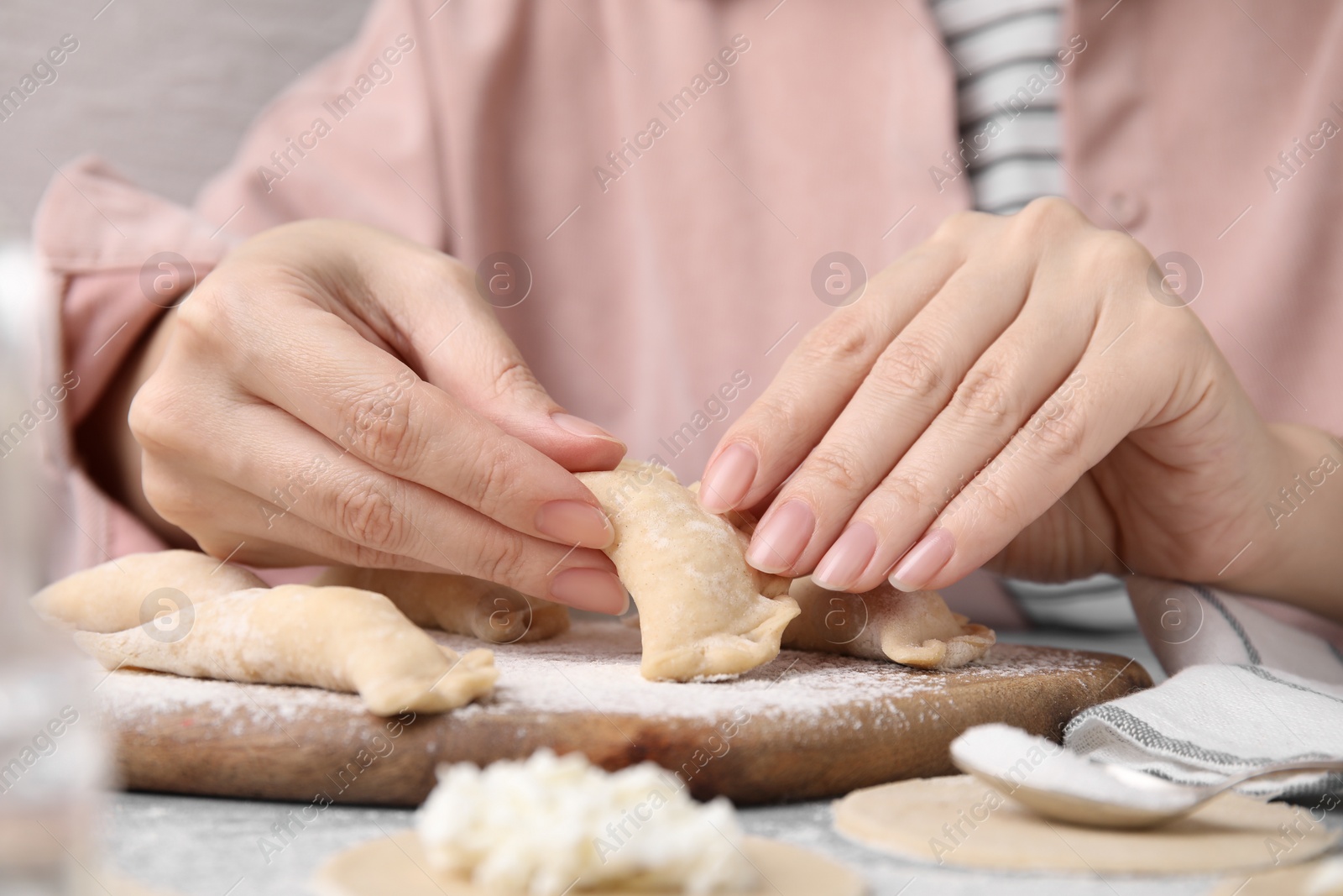 Photo of Woman making dumplings (varenyky) with cottage cheese at table, closeup