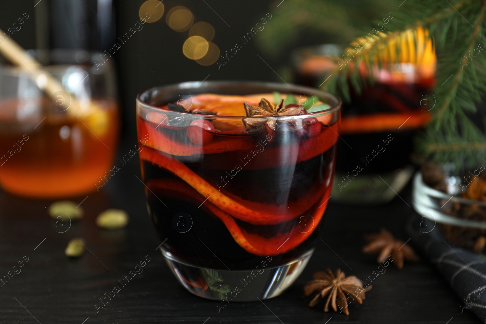 Photo of Glass cup of tasty mulled wine on black wooden table