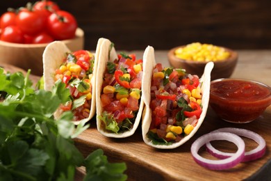 Tasty tacos with vegetables on wooden table, closeup