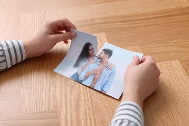 Photo of Woman ripping photo at wooden table, closeup. Divorce concept