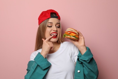 Pretty woman with tasty burger on color background